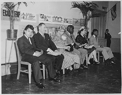 Eleanor Roosevelt and Jackie Robinson sit beside one another, while others are seated beside them.
